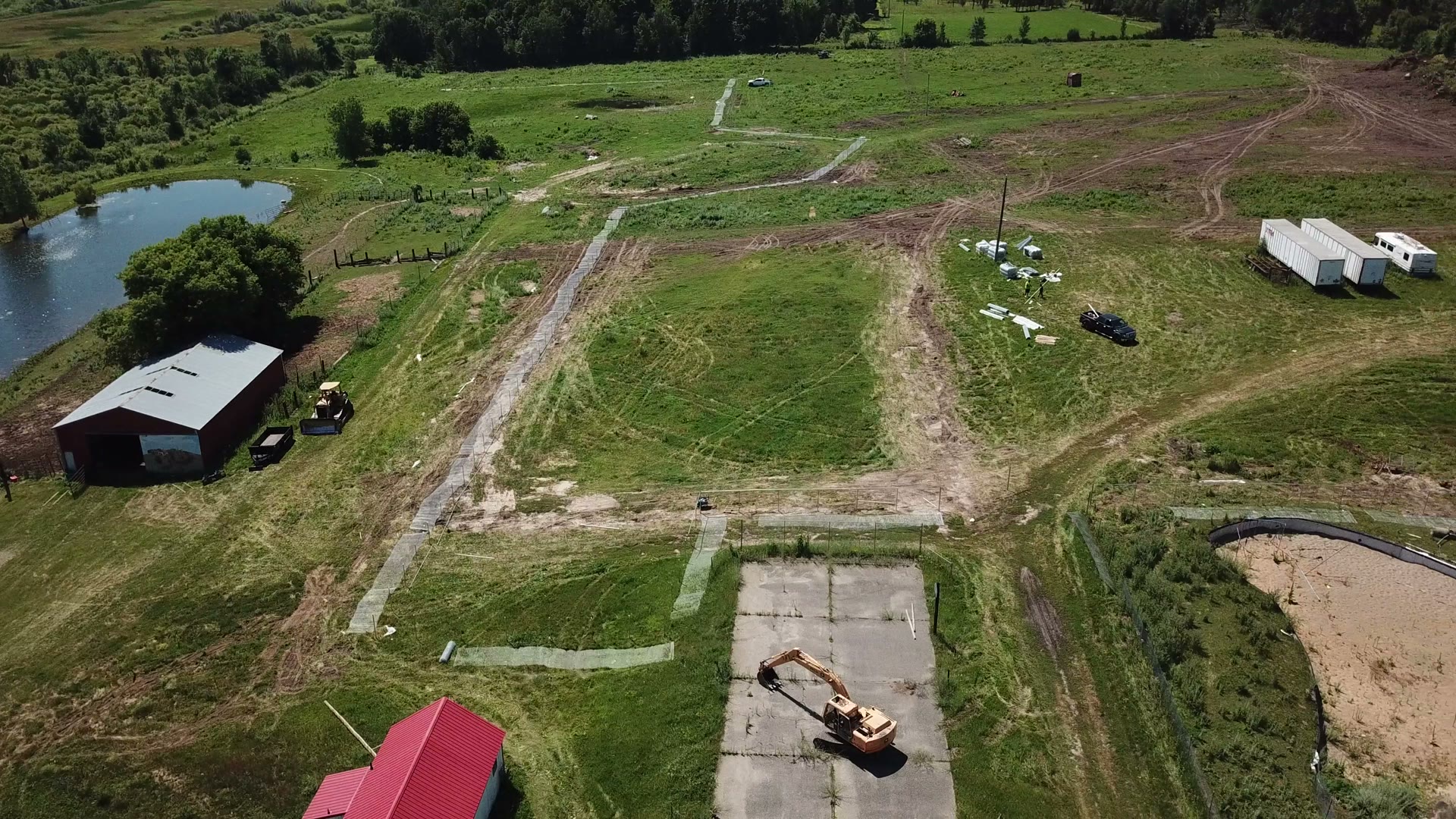 High aerial view of farm site with barn, pond, and equipment staging in Central Minnesota