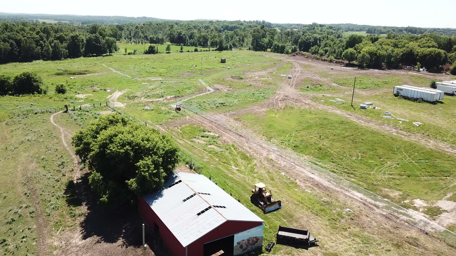 Aerial construction progress photo of a chain-link security fence line being installed across a Central Minnesota property