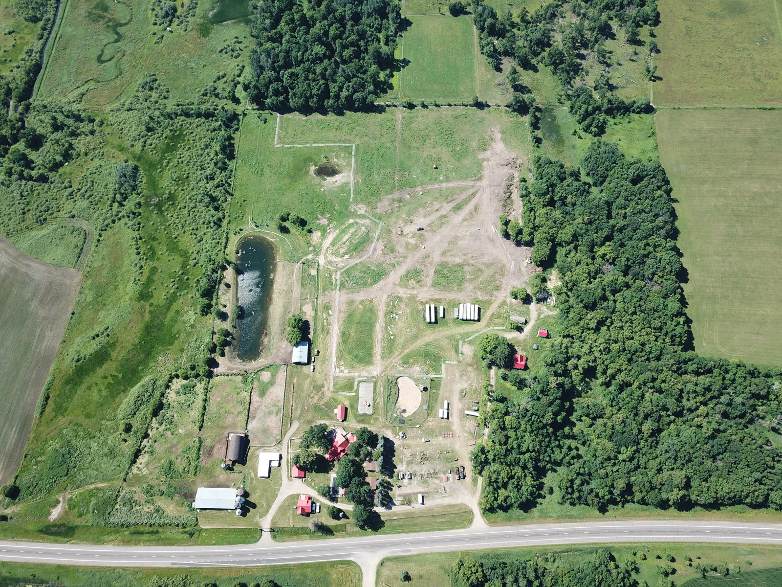 Top-down aerial documentation of a 100-acre Central Minnesota property showing buildings, pond, and fence lines